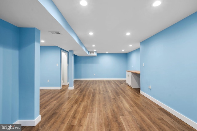 unfurnished living room with built in desk and hardwood / wood-style flooring