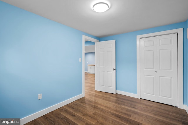 unfurnished bedroom with dark wood-type flooring and a closet