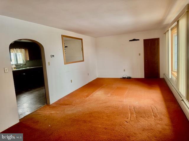 empty room with baseboard heating and carpet