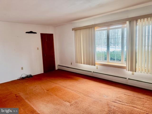 unfurnished room with baseboard heating and carpet flooring