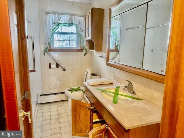 bathroom featuring toilet, tile patterned floors, vanity, and a baseboard heating unit