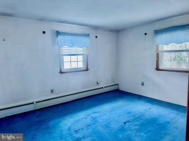 empty room featuring baseboard heating and dark colored carpet