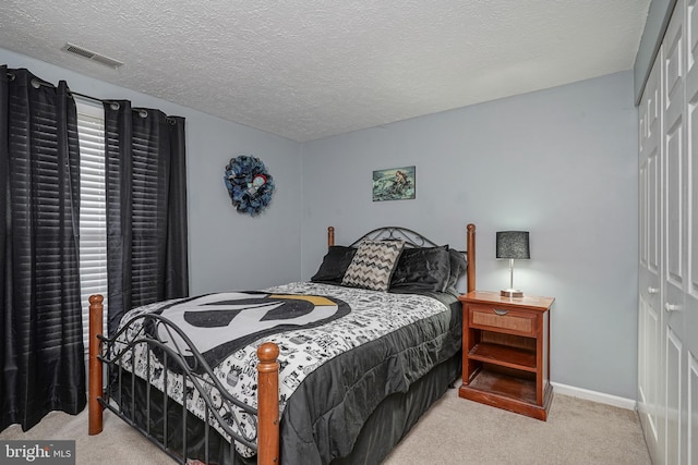 bedroom featuring a textured ceiling, a closet, and light colored carpet