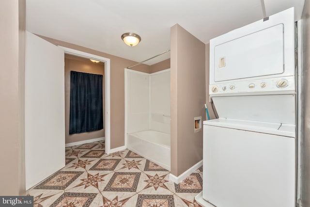 bathroom featuring stacked washing maching and dryer, bathing tub / shower combination, and tile patterned flooring