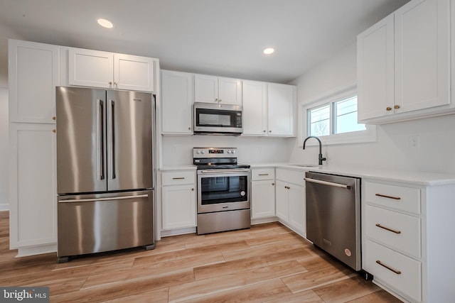 kitchen featuring appliances with stainless steel finishes, white cabinetry, and sink