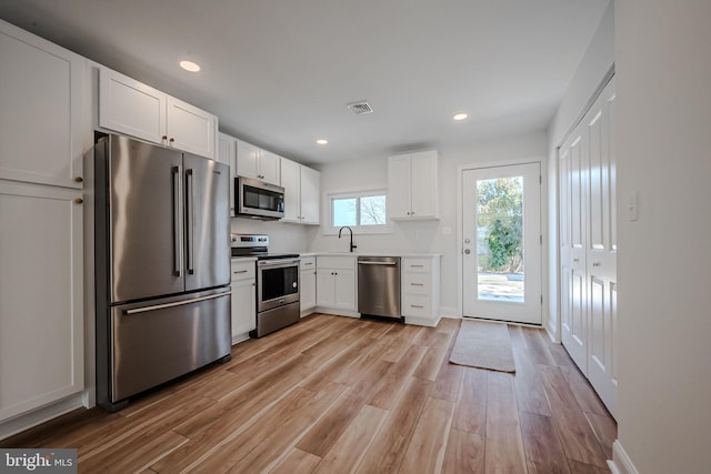 kitchen featuring stainless steel appliances, light wood-type flooring, white cabinets, and sink