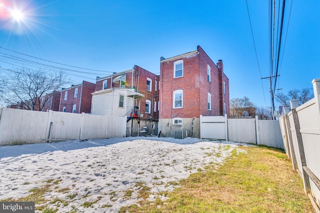 rear view of house featuring central air condition unit and a lawn