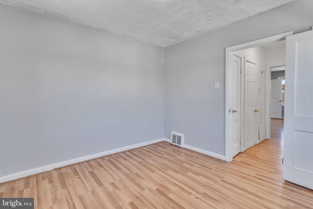 unfurnished room featuring a textured ceiling and light wood-type flooring