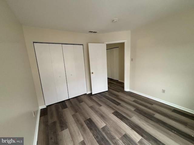 unfurnished bedroom with a closet and dark hardwood / wood-style floors