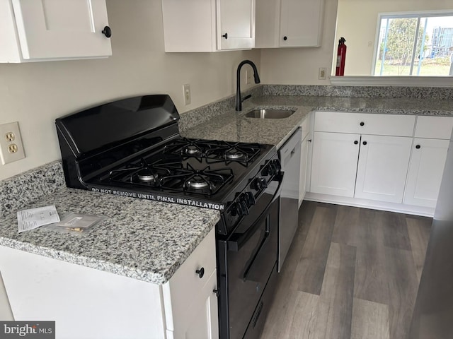 kitchen featuring dark wood-type flooring, light stone countertops, black range with gas stovetop, white cabinets, and sink