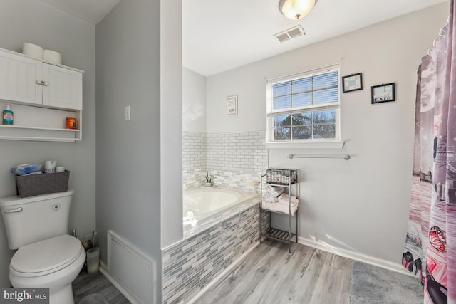 bathroom with toilet, wood-type flooring, and a relaxing tiled tub