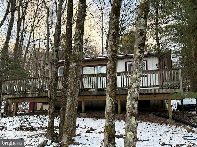 snow covered back of property featuring a wooden deck