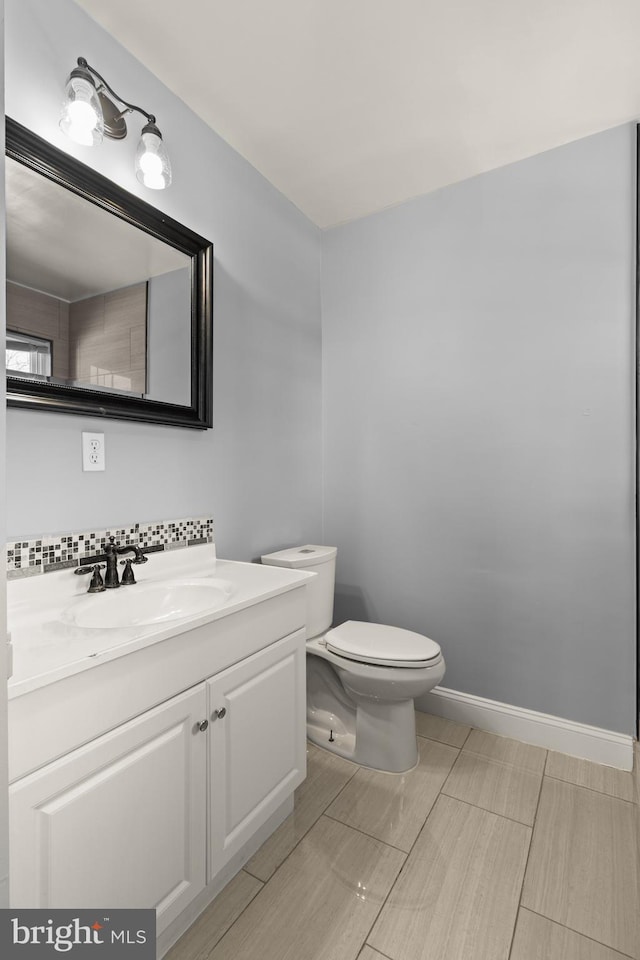 bathroom featuring backsplash, toilet, and vanity