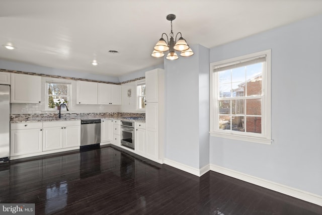 kitchen with pendant lighting, sink, white cabinetry, dark wood-type flooring, and appliances with stainless steel finishes