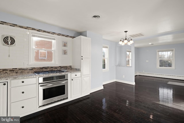 kitchen featuring backsplash, hanging light fixtures, appliances with stainless steel finishes, white cabinets, and a baseboard radiator