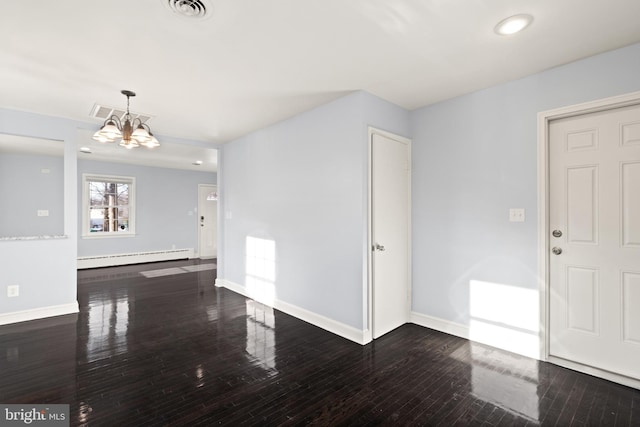 spare room with dark hardwood / wood-style flooring, a notable chandelier, and a baseboard radiator