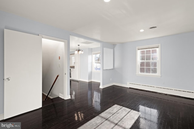 unfurnished room with a baseboard heating unit, dark wood-type flooring, and an inviting chandelier