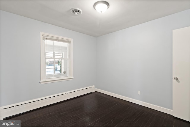 empty room featuring hardwood / wood-style flooring and a baseboard heating unit