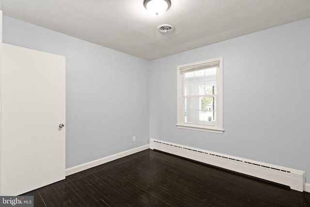 empty room featuring dark wood-type flooring and a baseboard heating unit