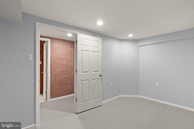 unfurnished room featuring brick wall