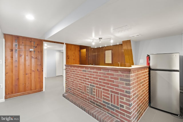 kitchen with stainless steel refrigerator and wood walls