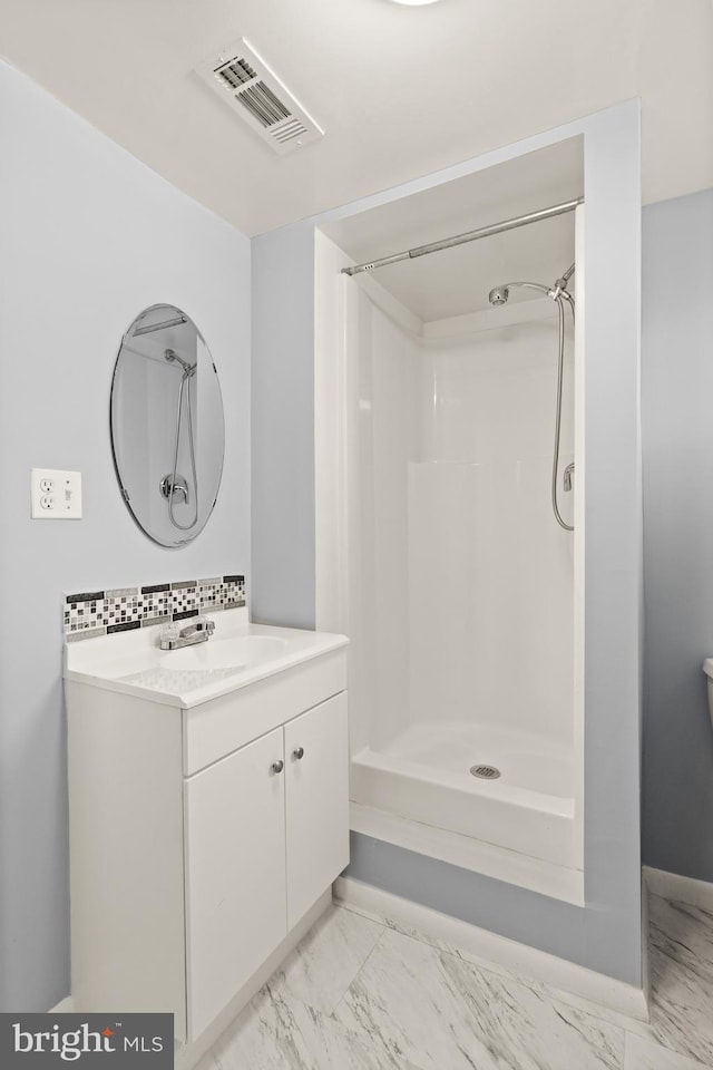 bathroom featuring walk in shower, vanity, and decorative backsplash