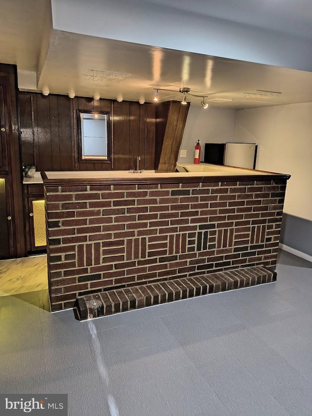 bar with dark brown cabinetry, wood walls, and light carpet