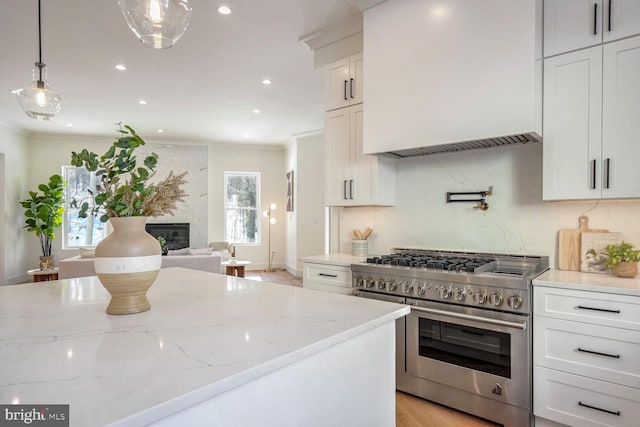 kitchen with decorative light fixtures, tasteful backsplash, white cabinetry, double oven range, and light stone countertops