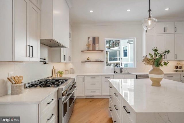 kitchen featuring sink, white cabinetry, double oven range, hanging light fixtures, and light stone counters