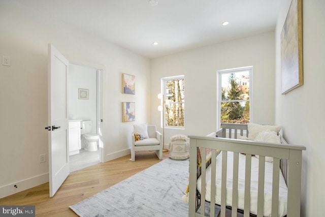 bedroom featuring ensuite bath and light wood-type flooring