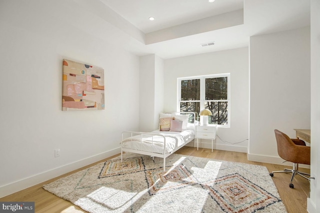 bedroom featuring a tray ceiling and light hardwood / wood-style flooring