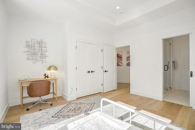 bedroom featuring hardwood / wood-style flooring, ensuite bath, and a closet