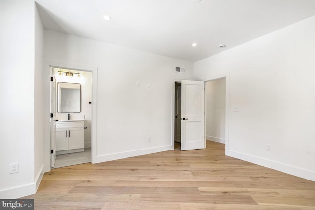 unfurnished bedroom featuring ensuite bath and light hardwood / wood-style flooring