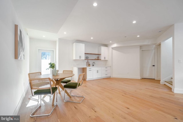 dining space with sink and light wood-type flooring