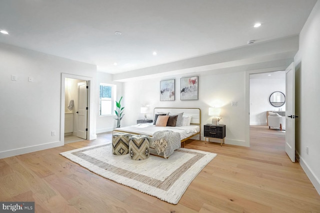 bedroom with connected bathroom and light wood-type flooring