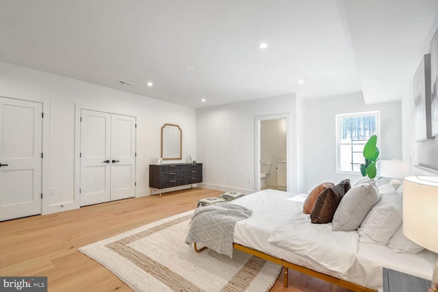 bedroom with connected bathroom and light wood-type flooring