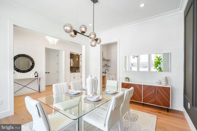 dining room with ornamental molding, an inviting chandelier, and light hardwood / wood-style floors