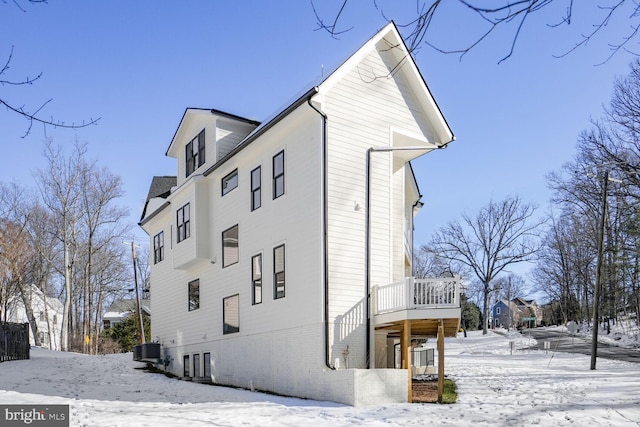 view of snow covered exterior with central AC and a wooden deck