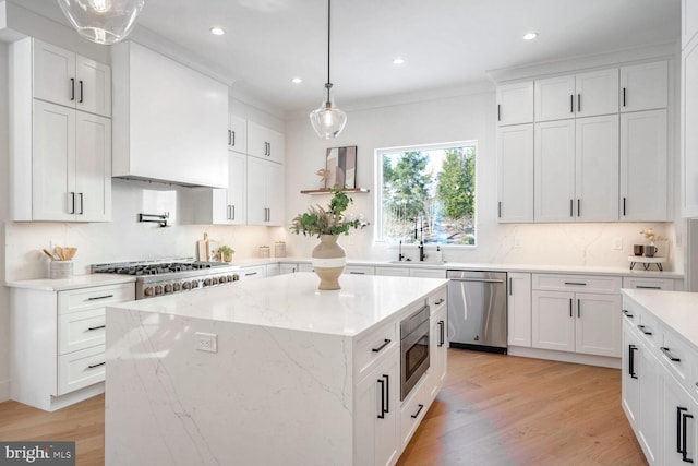 kitchen featuring sink, white cabinetry, a center island, hanging light fixtures, and stainless steel appliances