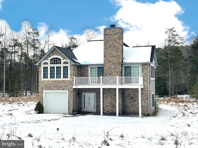 snow covered rear of property featuring a garage