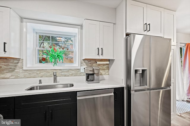 kitchen with appliances with stainless steel finishes, sink, white cabinets, and decorative backsplash