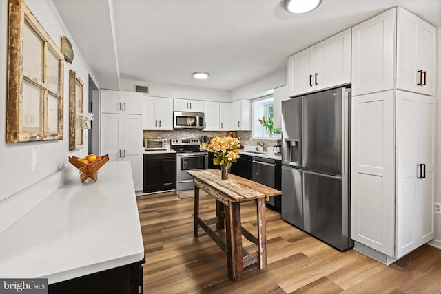 kitchen with white cabinetry, stainless steel appliances, and light hardwood / wood-style floors