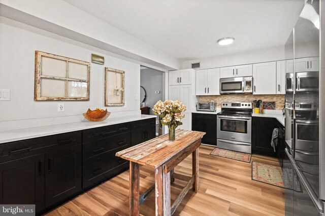 kitchen with white cabinetry, stainless steel appliances, decorative backsplash, and light wood-type flooring