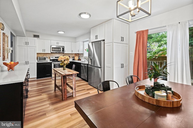 dining area with sink, a chandelier, and light wood-type flooring