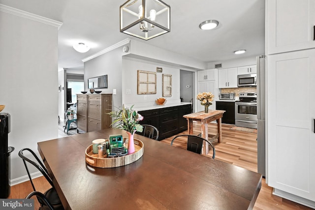 dining area with an inviting chandelier, light hardwood / wood-style flooring, and ornamental molding