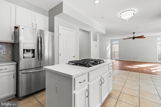 kitchen featuring white cabinetry, tasteful backsplash, light tile patterned floors, a kitchen island, and stainless steel appliances