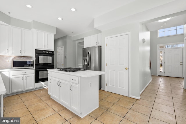 kitchen featuring light tile patterned flooring, a kitchen island, appliances with stainless steel finishes, white cabinets, and decorative backsplash