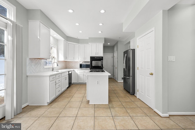kitchen with light tile patterned flooring, appliances with stainless steel finishes, white cabinetry, backsplash, and a center island