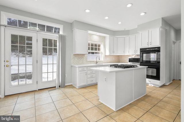 kitchen with light tile patterned floors, sink, white cabinetry, stainless steel appliances, and a center island