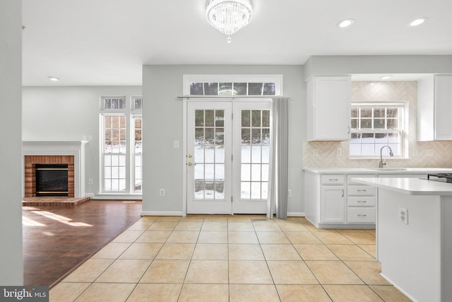 interior space with backsplash, plenty of natural light, white cabinets, and light tile patterned flooring